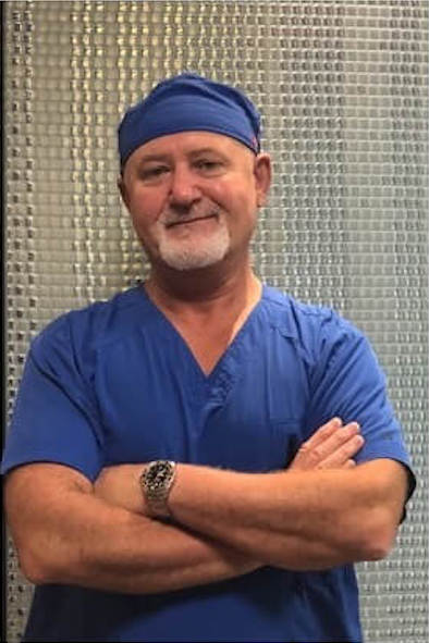 dentist wearing blue scrubs and cap with arms crossed